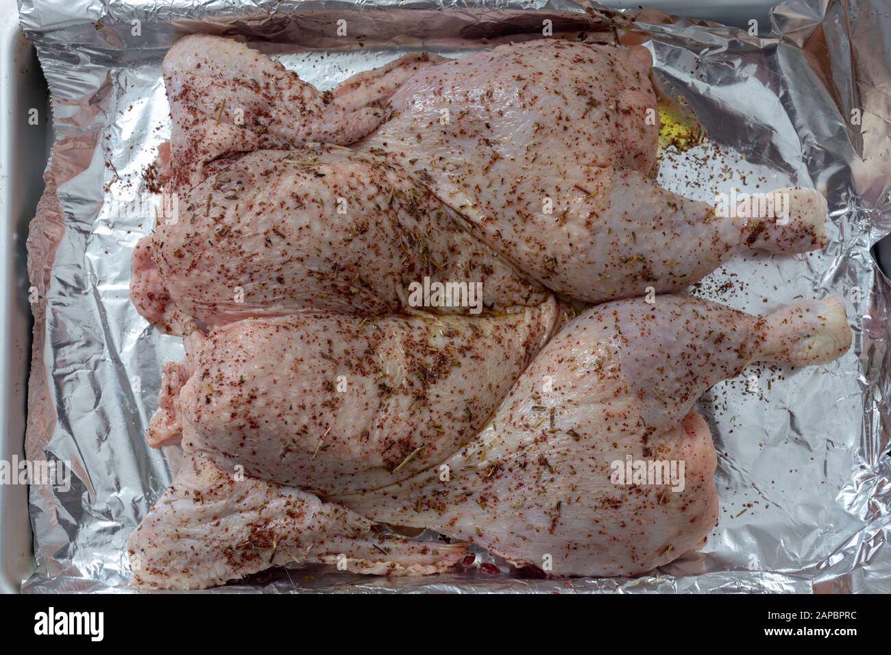 A spatchcocked chicken rubbed with herbs, lemon and oil, ready for the oven Stock Photo