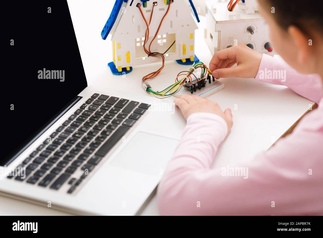 Girl constructing robot and programming it on laptop Stock Photo