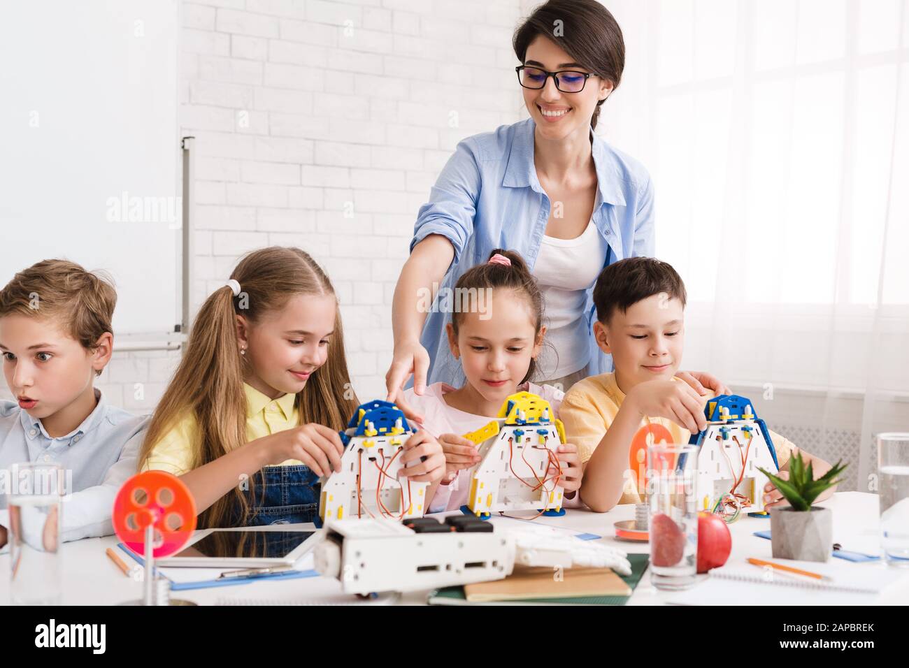 Pupils constructing modern robots with teacher's help Stock Photo - Alamy