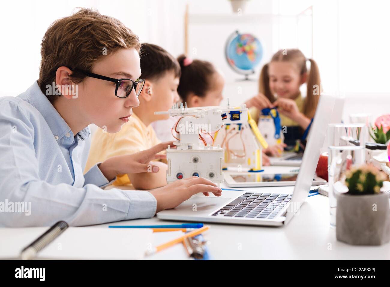 Creating robots. Concentrated boy typing on laptop Stock Photo