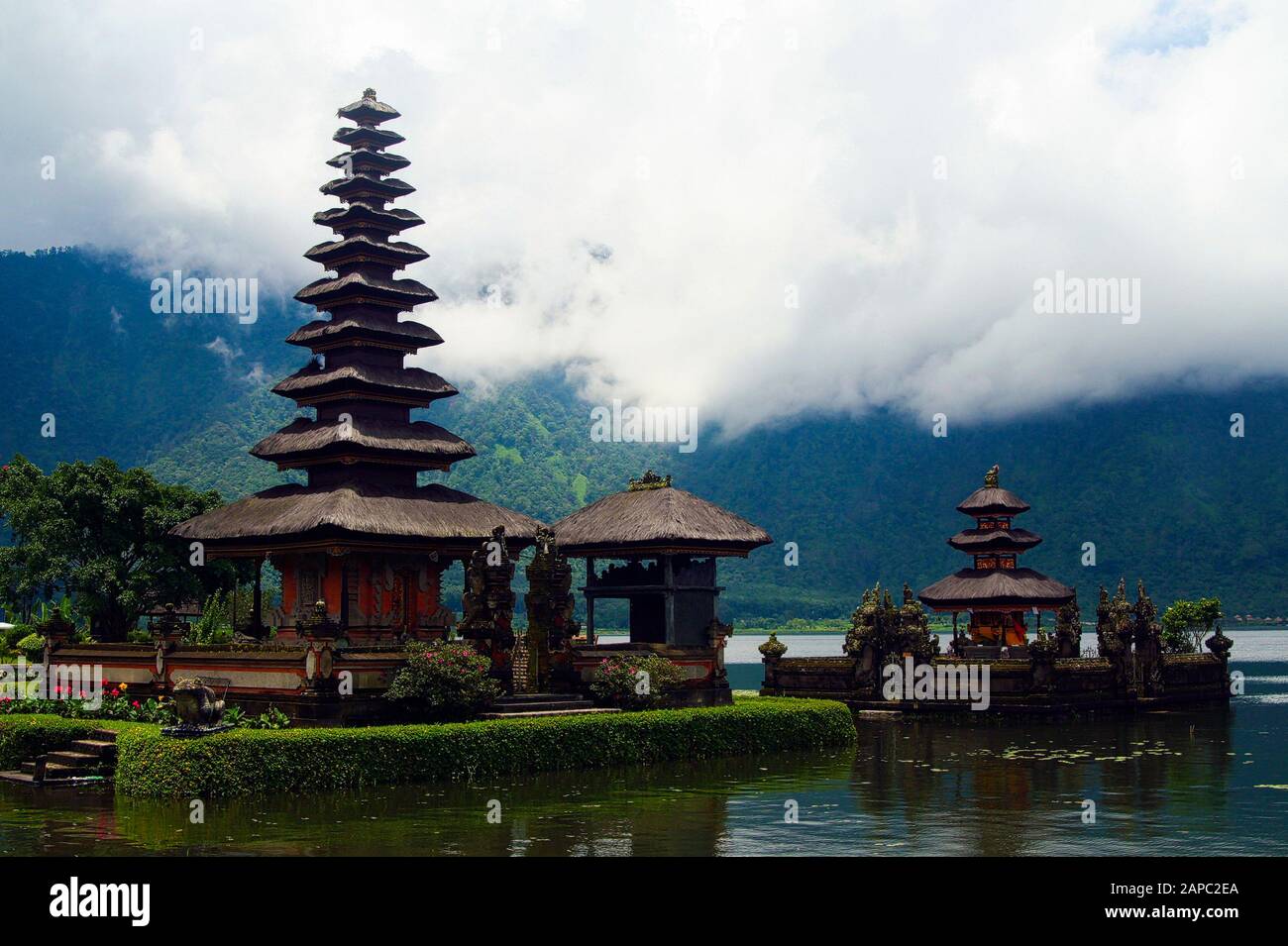 Moody atmosphere with low hanging clouds fog over lake at Pura Ulun Danu Batur temple on Bratan lake - Bali Stock Photo