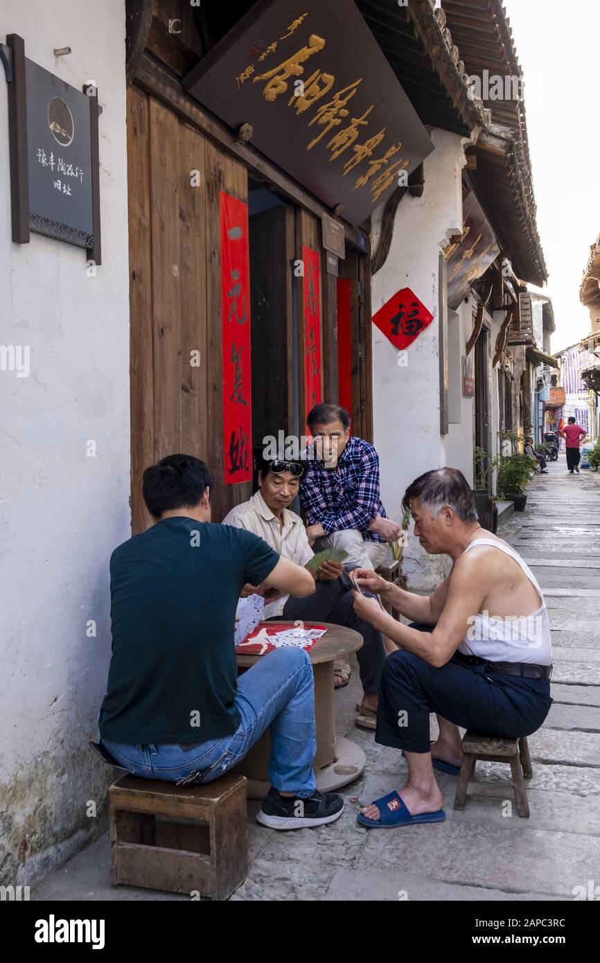 Locals playing cards in an old city street in China Stock Photo