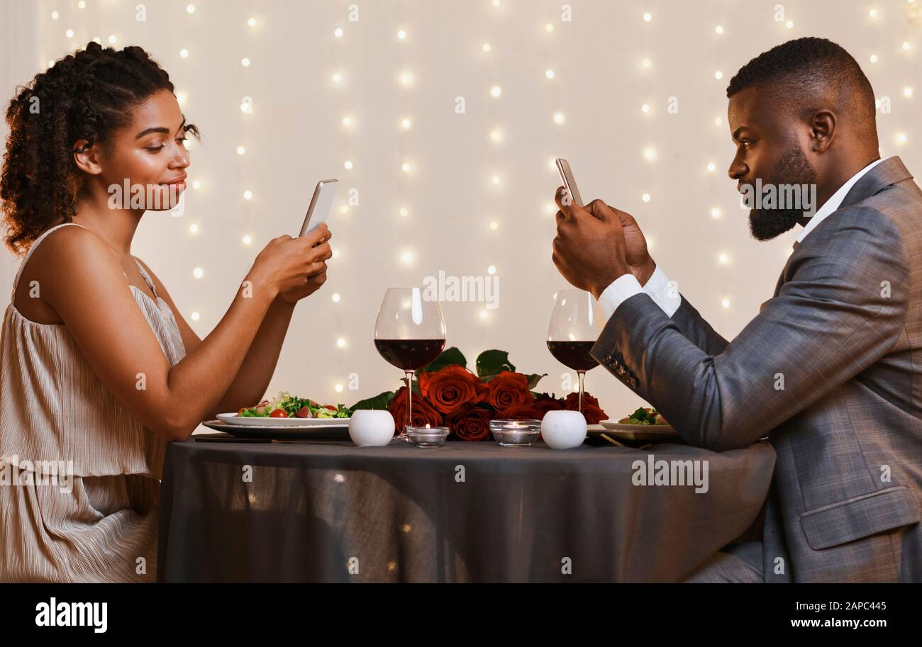 Young couple using mobile phones while date at restaurant Stock Photo