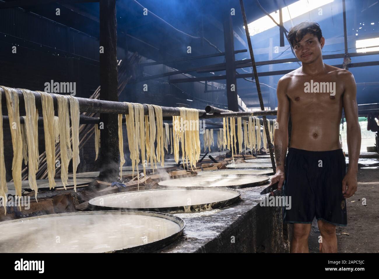 A worker making edible rice paper using the pith from rice heated in bowls, Koh Dach (Silk Island), Phnom Penh, Cambodia Stock Photo