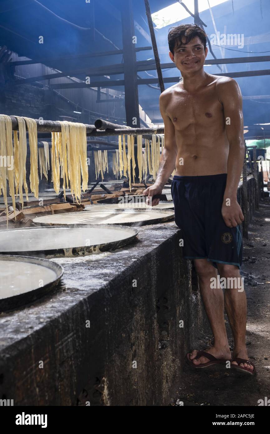 A worker making edible rice paper using the pith from rice heated in bowls, Koh Dach (Silk Island), Phnom Penh, Cambodia Stock Photo