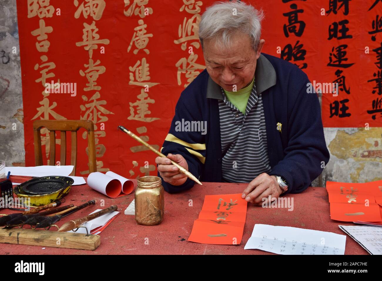FOSHAN, CHINA - CIRCA JANUARY 2020: A man writing blessing couples during the Spring Festival. A translation of couplets is Happy and prosperious year Stock Photo