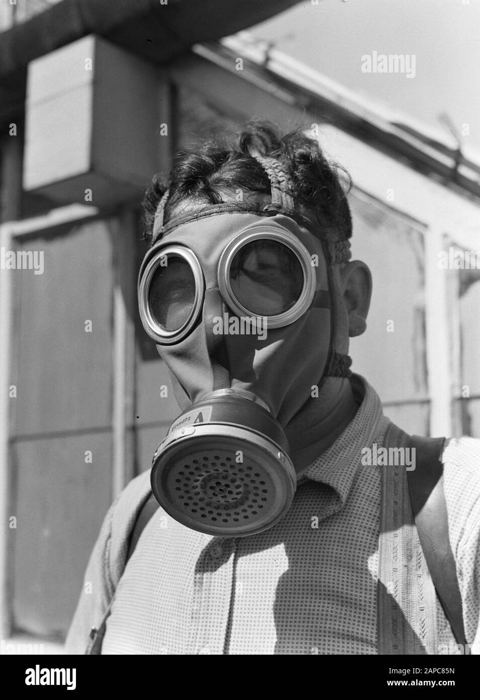 Product photos; plant greenhouse Description: Aalsmeer. an employee of  nursery Baardse with gas mask against the inhalation of insecticides when  spraying plants in the greenhouses Date: 1930 Location: Aalsmeer, Noord-  Holland Keywords: