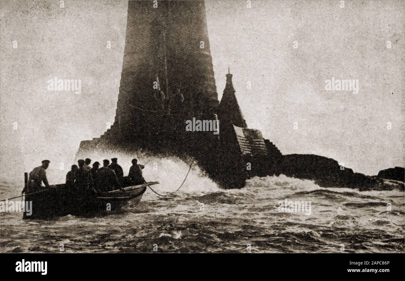 C1930s Relief lighthouse keepers arriving  in a rowing boat at Wolf Rock Lighthouse (Cornwall, England) in a heavy swell. Situated between St Mary's, Isles of Scilly and The Lizard near  Lands End. It gets its name from the howling sounds produced by wave action on the rocks  during stormy weather. A metal effigy of a wolf was placed on top as a daymark  but was washed away in the late 1700s. The Cornish name for the rocky outcrop is An Welv meaning The Lip. It was  the first lighthouse  in the world to be fitted with a helipad.  James Walker built the cone shaped beacon next to it in 1848. Wo Stock Photo