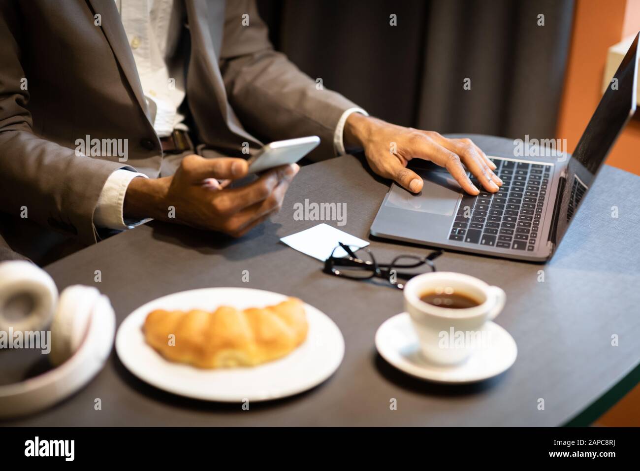 Cropped image of busy afro guy using phone and computer Stock Photo