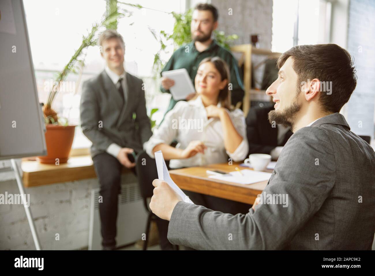 For ideas. Group of young business professionals having a meeting. Diverse group of coworkers discuss new decisions, plans, results, strategy. Creativity, workplace, business, finance, teamwork. Stock Photo
