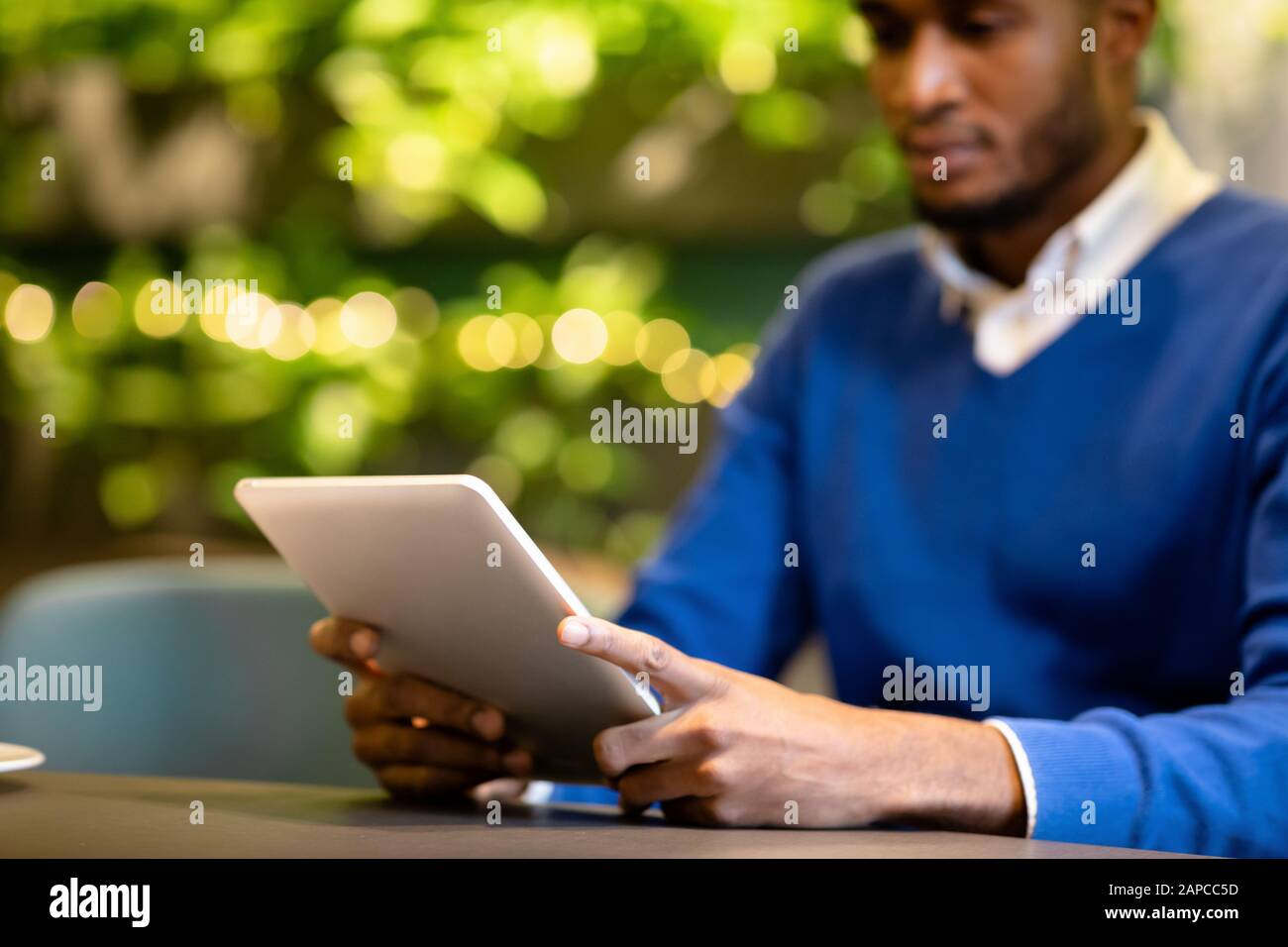Black guy sitting in coffee shop working on tablet Stock Photo