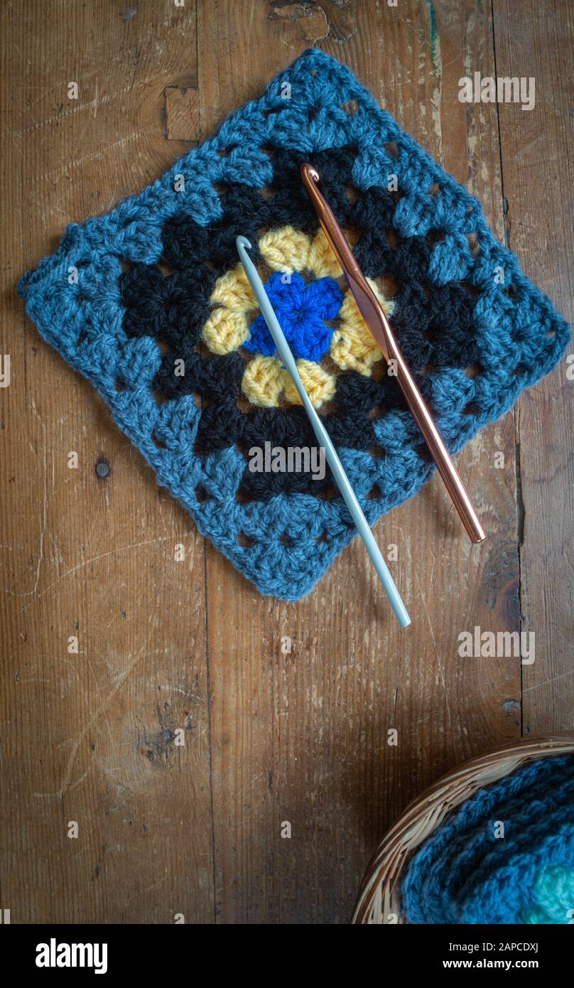 granny square with crochet hooks on wooden table ,top view. Stock Photo