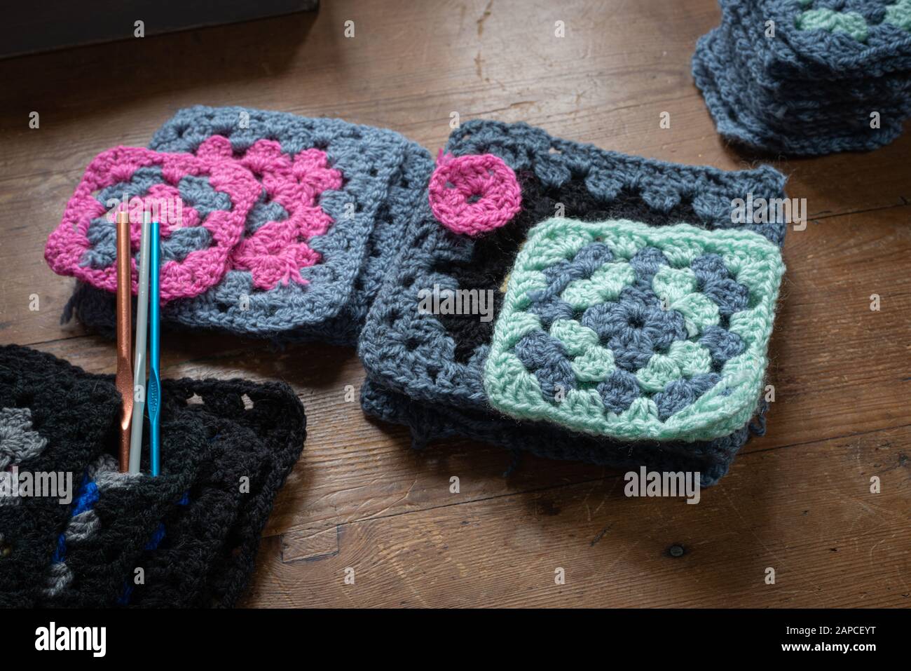 hand made crochet granny squares with crochet hooks on wooden table. Stock Photo