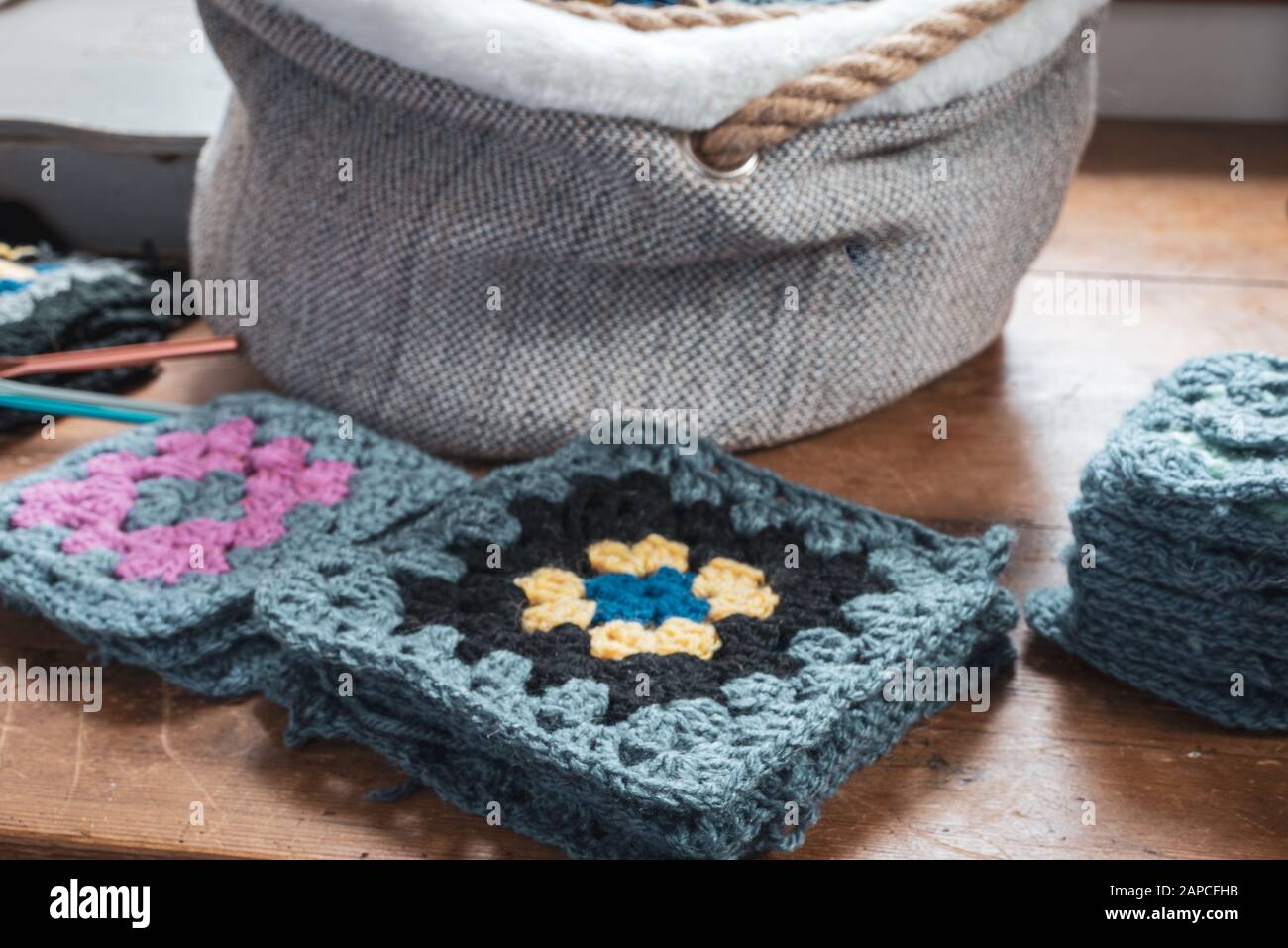 hand made crochet granny squares on wooden table. Stock Photo