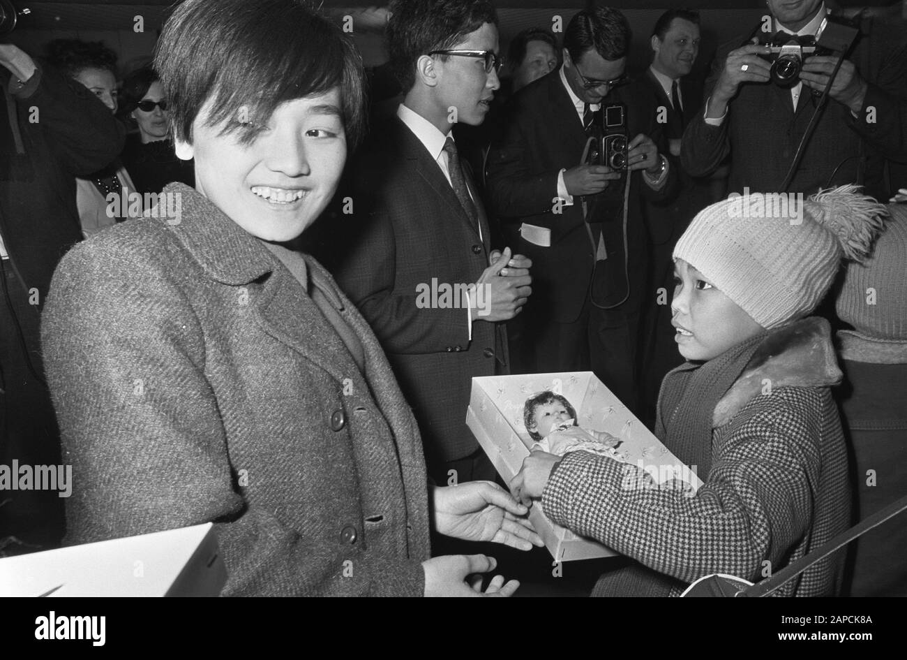 Arrival Vietnamese children at Schiphol. Troug Phai Anh Dao gives Le Thi Trai a doll upon arrival Date: 20 December 1967 Location: Noord-Holland, Schiphol Keywords: Children, arrivals Stock Photo