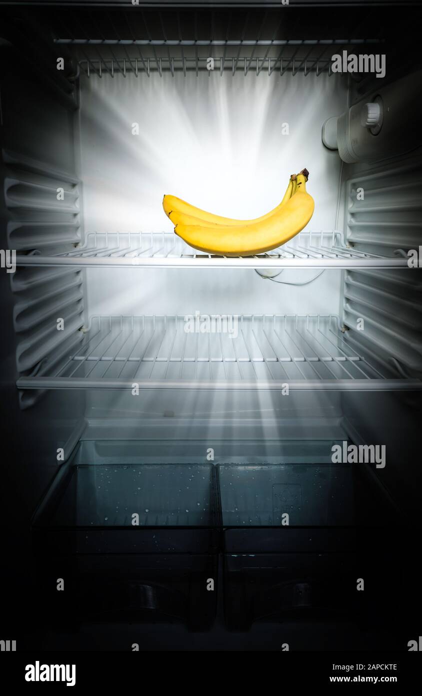 Bright fresh bananas glowing in the dark on shelf of open empty