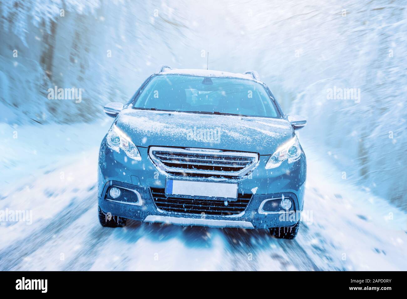 Car drives through the snow. Winter driving concept. Road and trees in motion. Front view of the car on the road Stock Photo