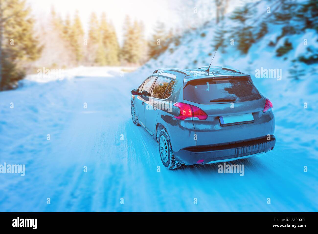 Car drives through the snowy mountain. Rear view of car and road. Concept of safe driving with winter tires Stock Photo