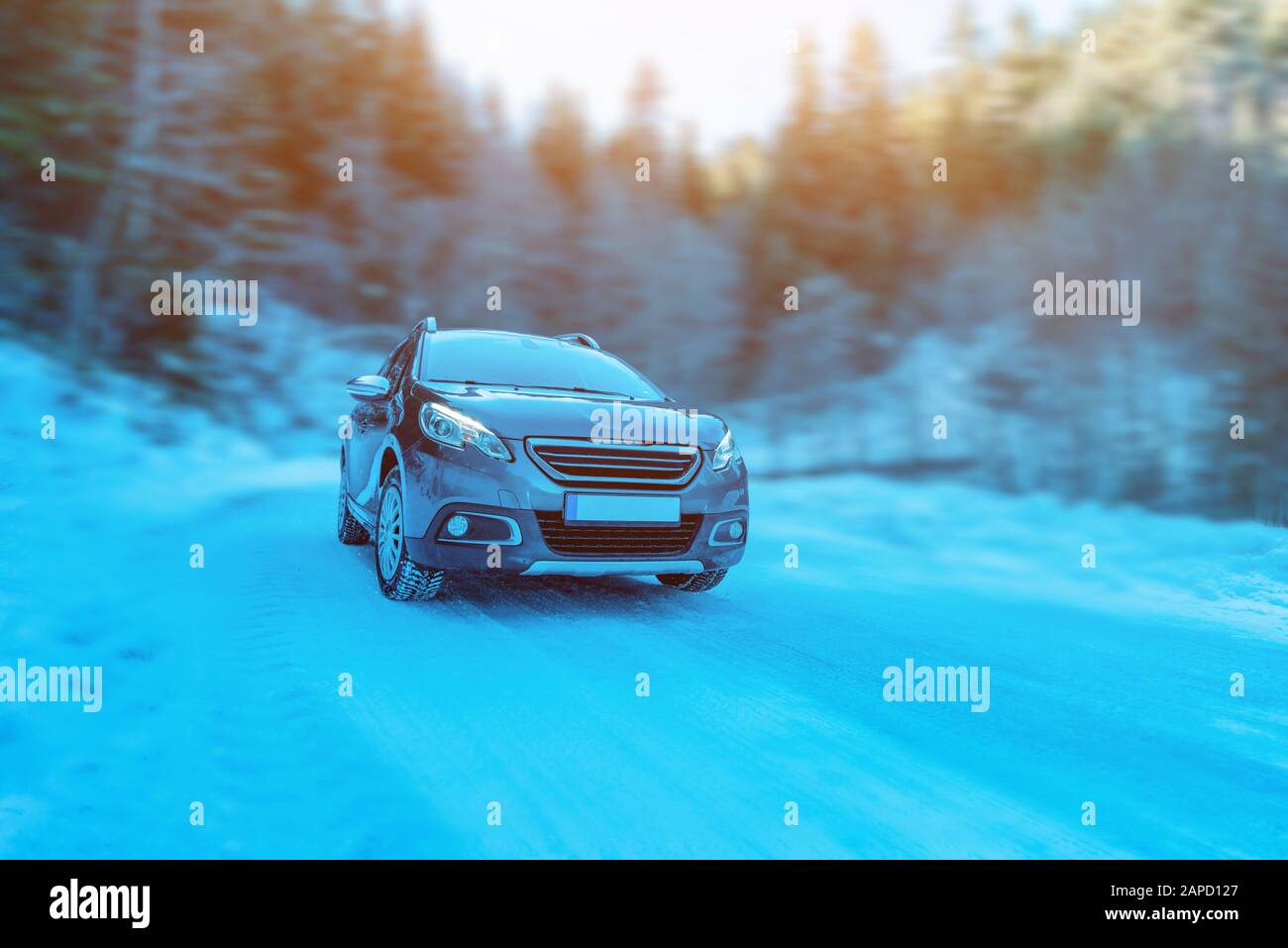 A car on a snowy mountain road. The concept of traveling and driving in winter conditions. Trees in the background. Cold, winter time Stock Photo