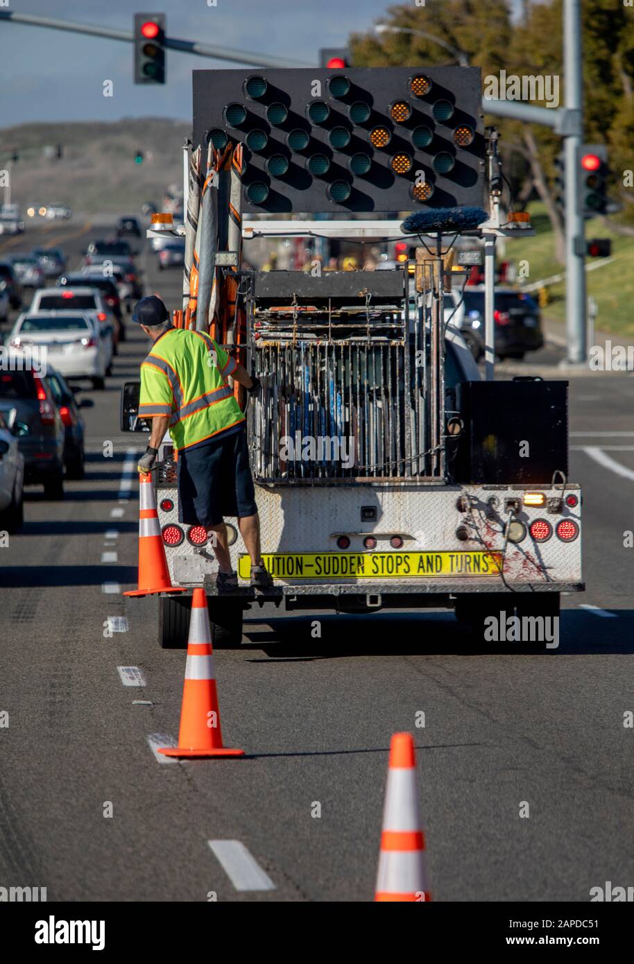 Worker behind utility truck placing bright orange traffic cones on