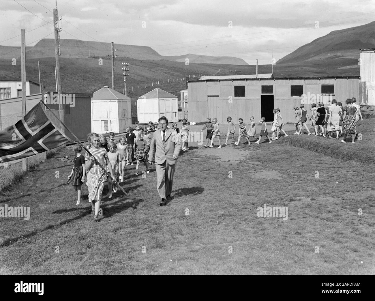 Iceland Description: Alafoss. Row young girls with the Icelandic flag in front, marching across the terrain, accompanied by businessman Sigurjón Pétursson Date: 1934 Location: Iceland, Àlafoss Keywords: children, marching, entrepreneurs, flags Personal name: Pétursson, Sigurjón Stock Photo
