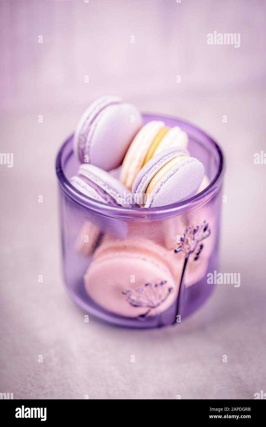 Pale purple glass with macaroons or macarons on the gray background. Glassware made of recycled glass, eco friendly concept. Copy space Stock Photo