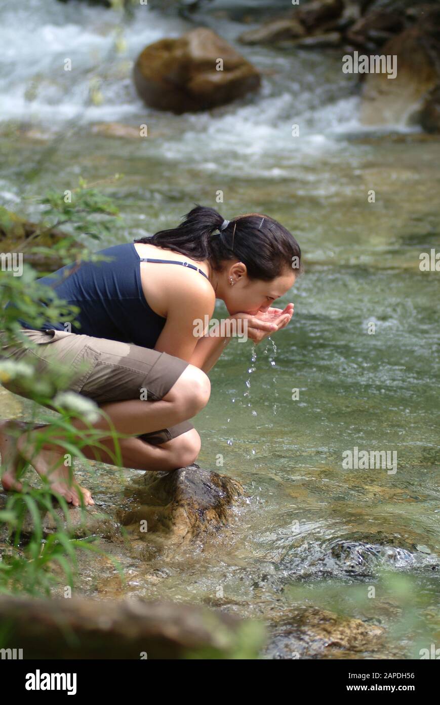 Junge Frau trinkt Wasser aus einem Bach - Young Woman drinking Water out of  a River Stock Photo - Alamy