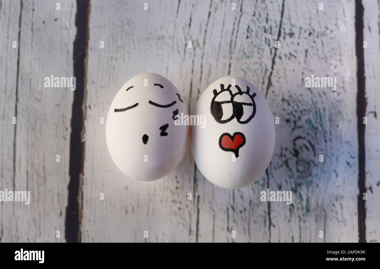 White eggs with faces painted in the shell, isolated on a white wooden background Stock Photo