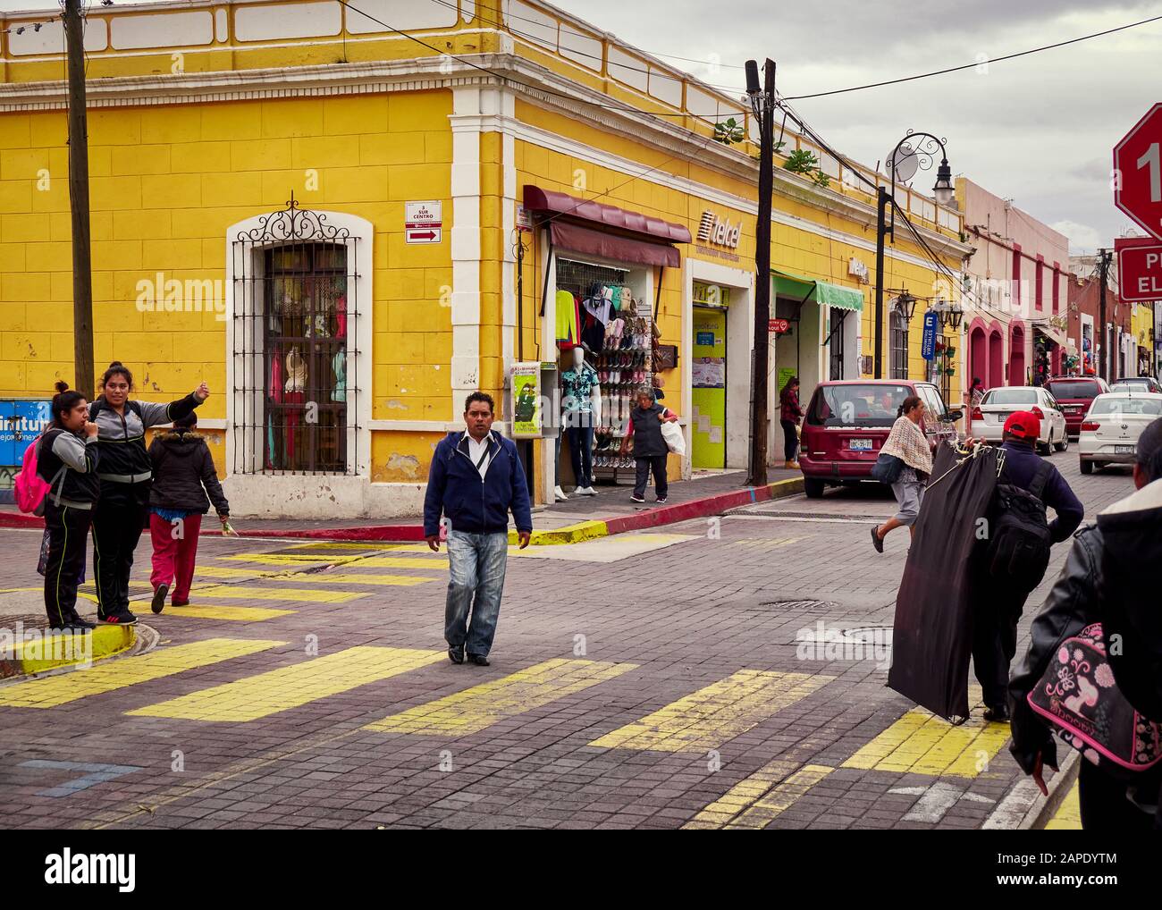 San Pedro Cholula, Mexico, October 17, 2018 - Yellow pedestrian crossing with people walking and man in the middle of the street in San Pedro Cholula Stock Photo