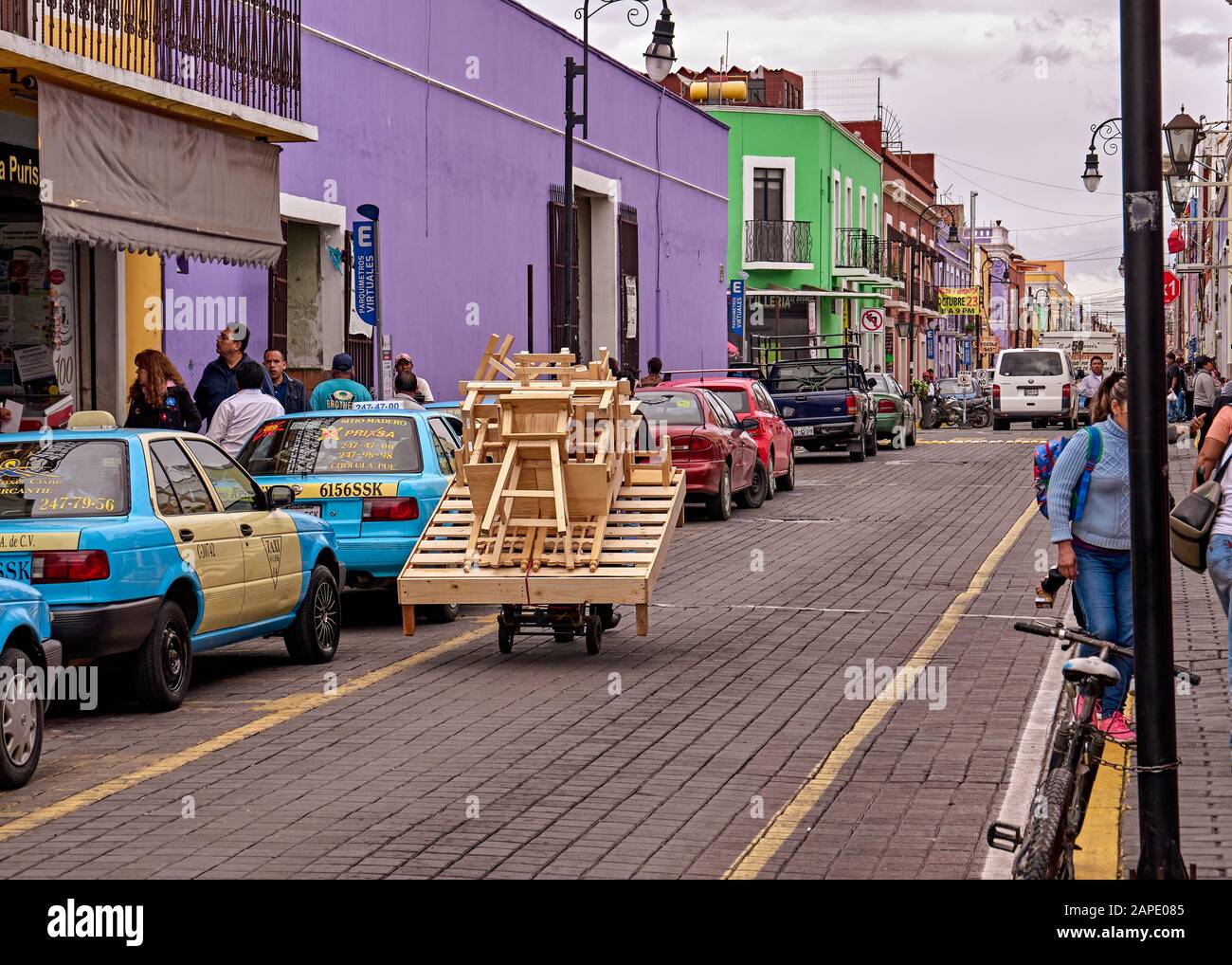 San Pedro Cholula, Mexico, October 17, 2018 - Carpenter transports furniture by hand in handcart between cars on the street of San Pedro Cholula. Stock Photo