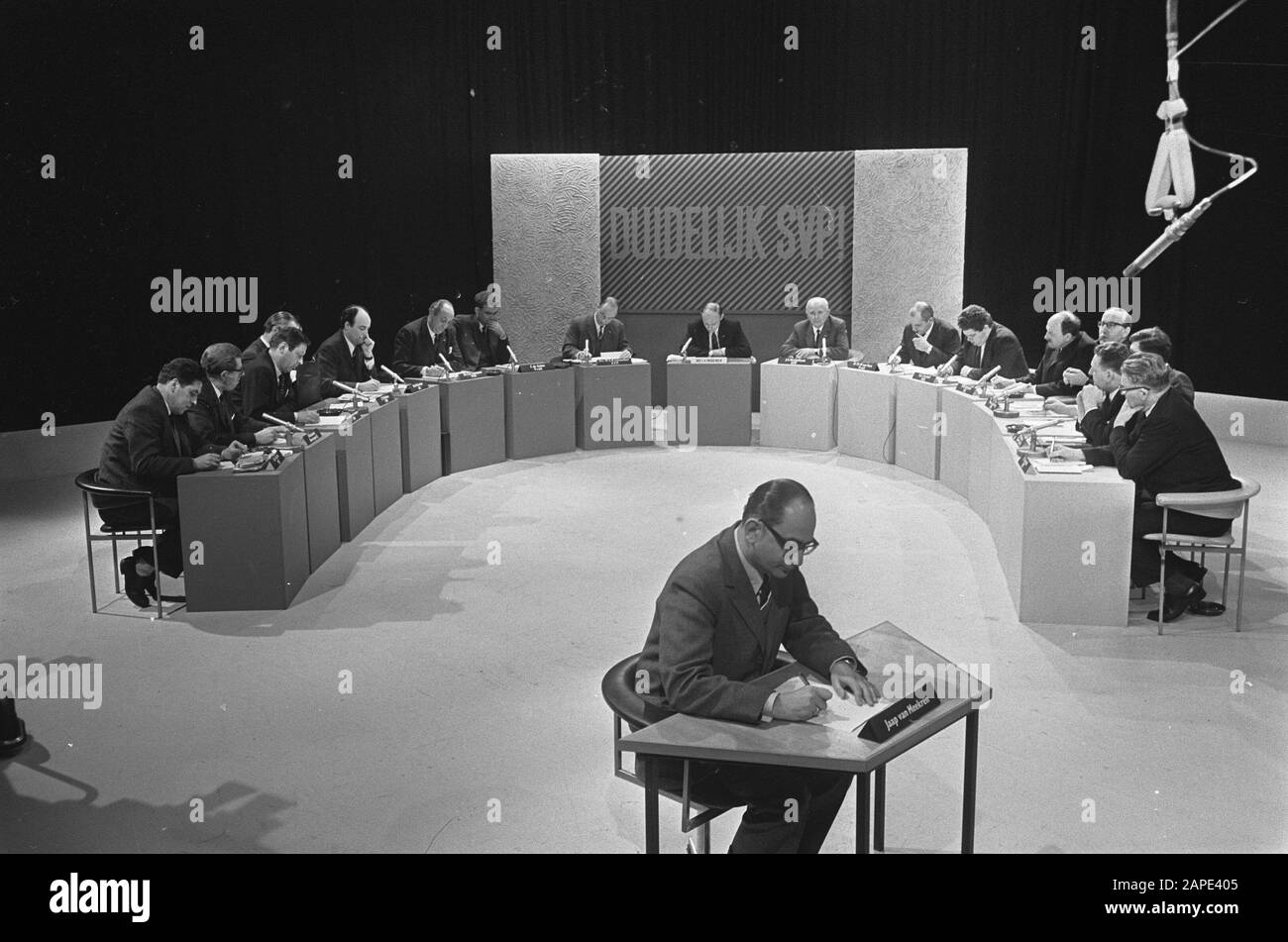 AVRO-TV, Clear svp, sixteen Dutch politicians debate under the direction of drs. F. A. Hoogendijk (middle) Annotation: To see are a.o. vlnr. F. van der Spek (PSP), W. Koekoek (Farmers' Party), Lookeren Campagne (D66), Mellema (CHU), W. Aantjes (ARP) E.H. Toxopeus (VVD), C. de Galan (PvdA), Schmelzer (KvP), F. Hoogendijk, J. Middelhuis (KVP), Th. W. van Veen (PvdA), Vonhoff (VVD), M.W. Switch (ARP), H.A. Schuring (CHU). In the foreground presenter Jaap van Meekren (AVRO) Date: 5 February 1968 Location: Hilversum Keywords: debates, politics, television programs, television studios Stock Photo