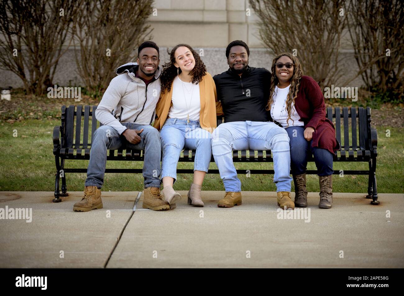 Group of people sitting on a bench in a park under sunlight with a