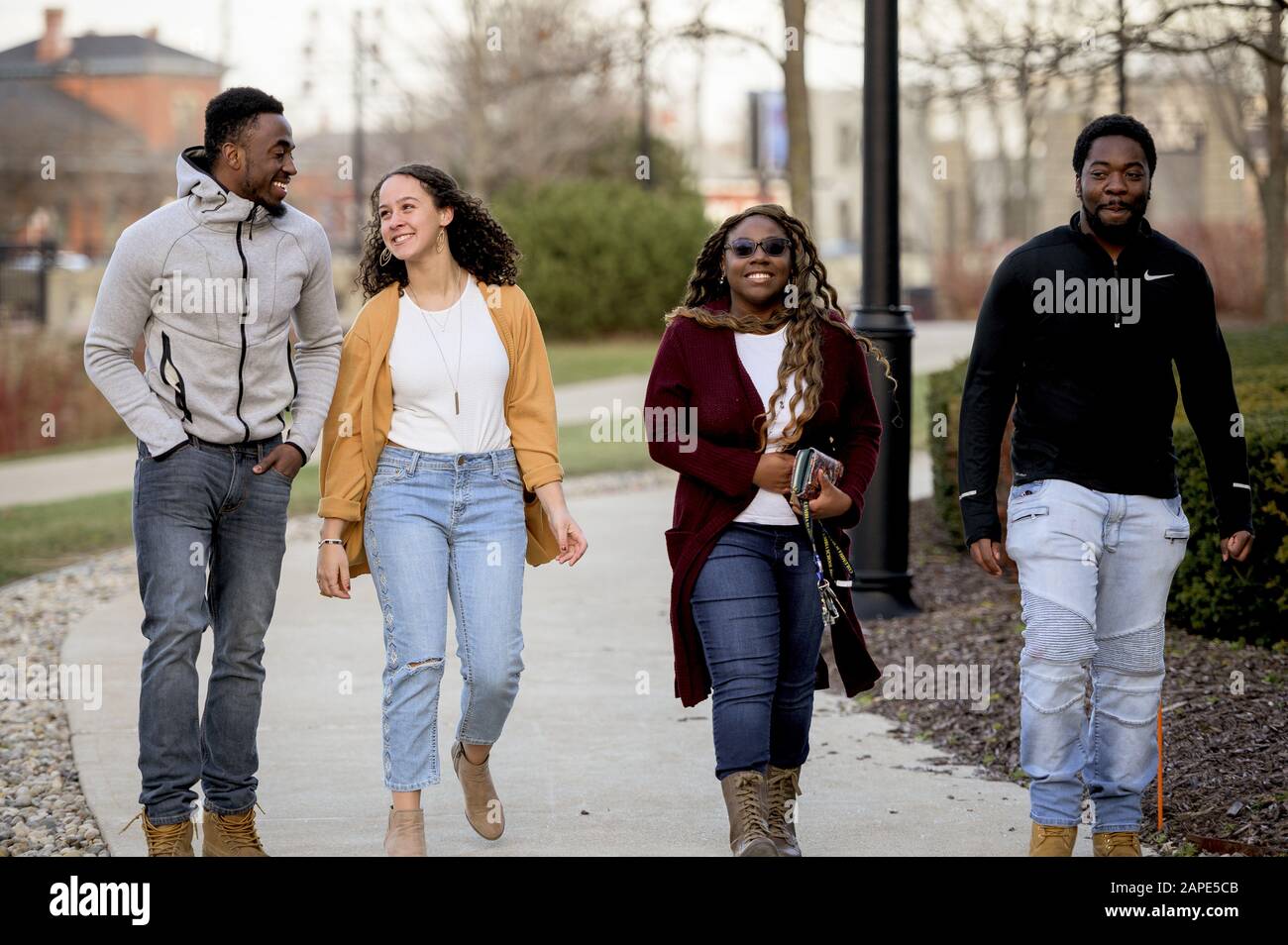 Group of people walking through a park under sunlight with a blurry ...