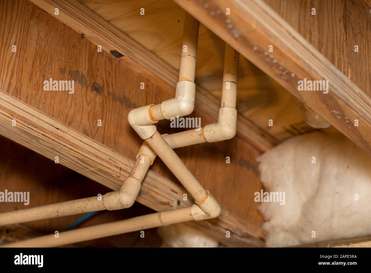 Old PVC plastic water supply pipes installed under house in crawlspace. Hot and cold water plumbing system for bathroom sink and shower Stock Photo