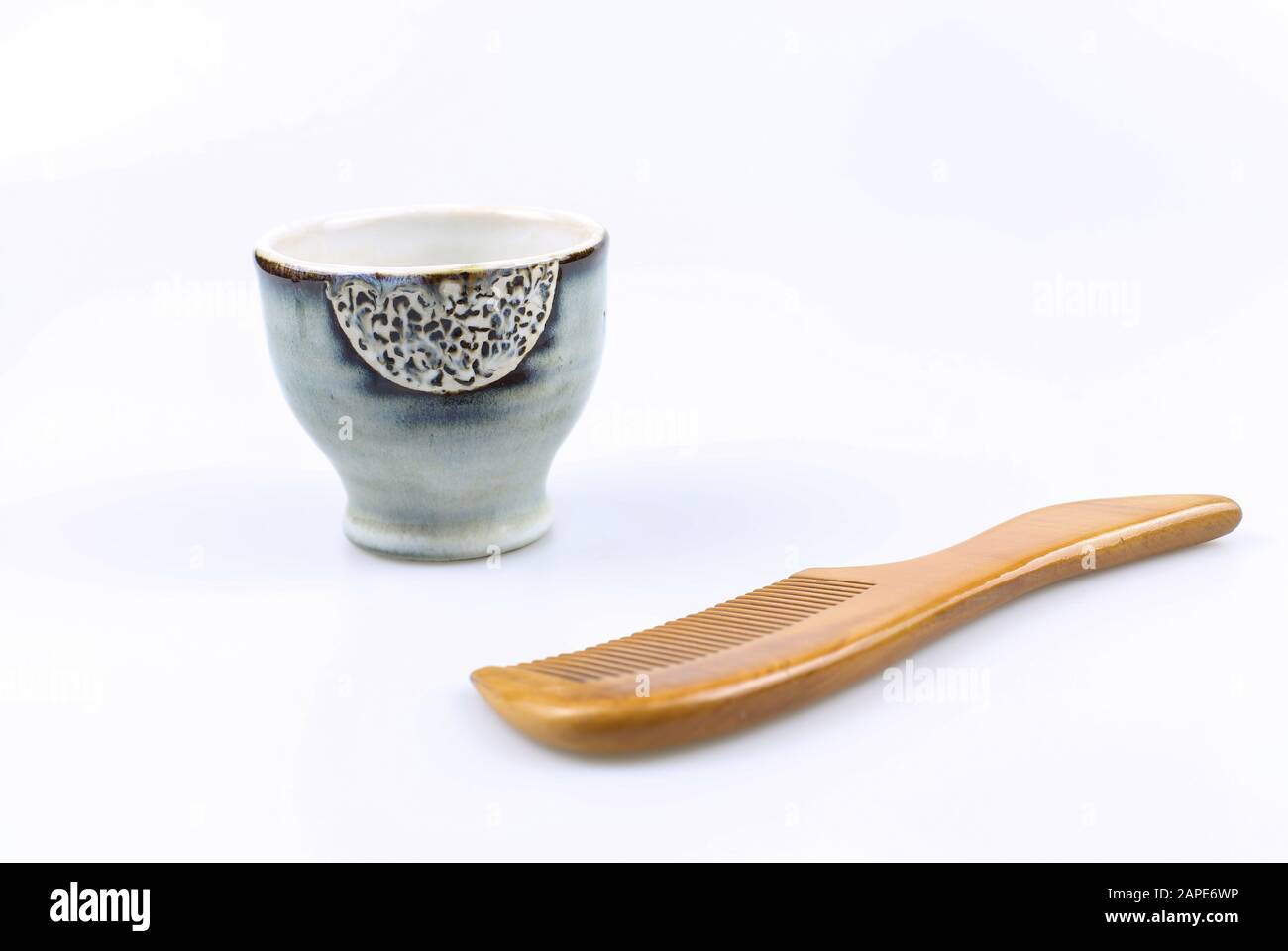 Chinese comb and a teacup on a white surface Stock Photo