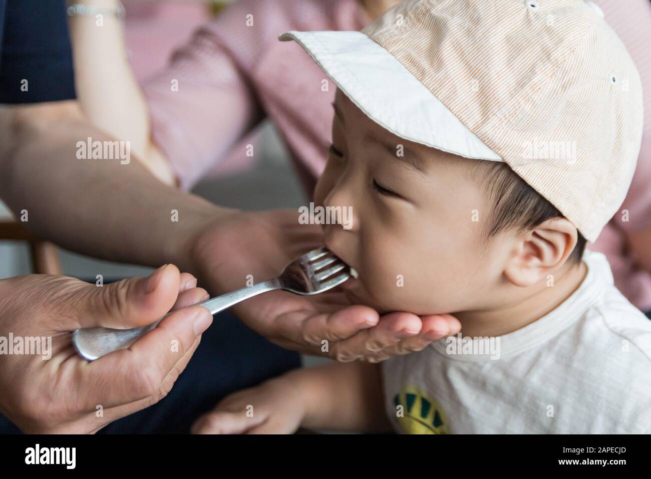 Little asian boy eating bread at cafe Stock Photo