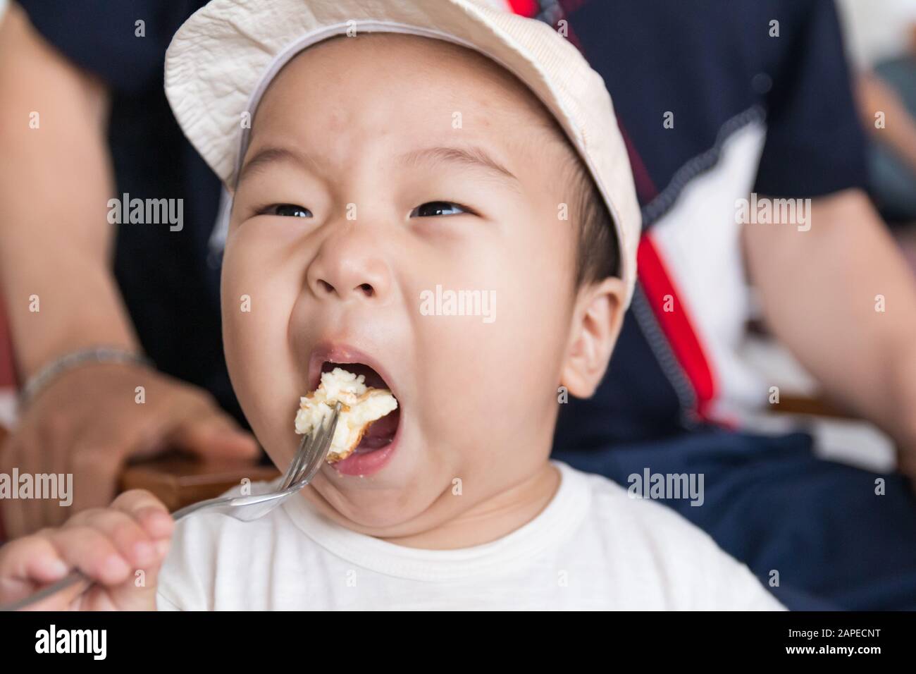 Little asian boy eating bread at cafe Stock Photo