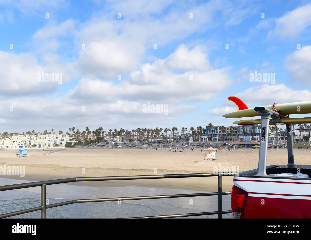 HUNTINGTON BEACH, CALIFORNIA - 22 JAN 2020: Surfboard on Lifeguard truck rack on the pier with beach and town in the background. Stock Photo