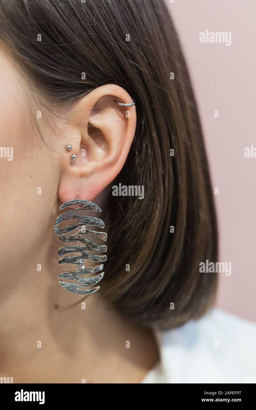 trendy stylish silver earrings on the girl's ear with bob haircut