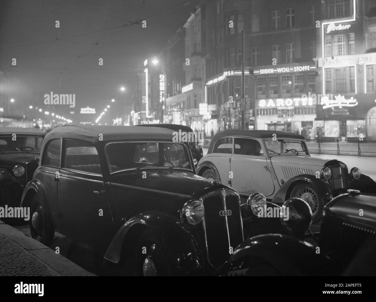 Reportage Berlin Description: Berlin. Night shooting of the Tauentzienstrasse with the illuminated facade of the cafe-restaurant Pschorr-Brau and the chocolate shop Sarotti and packed cars Date: November 1935 Location: Berlin, Germany Keywords: cars, cafes, chocolate, advertising, restaurants, cityscape Stock Photo