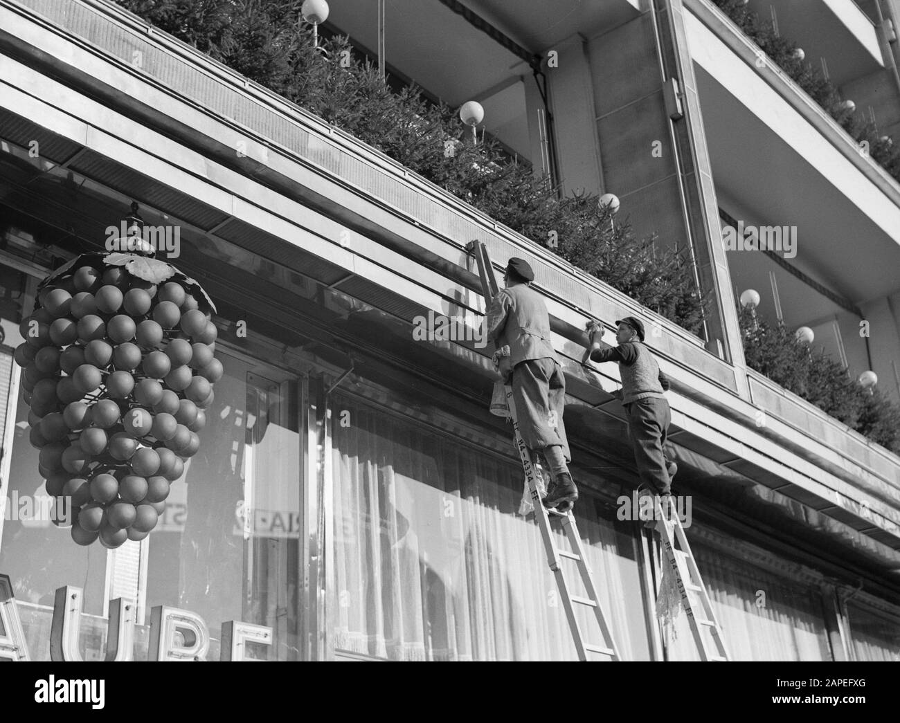 Reportage Berlin Description: Berlin. Painters at work on ladders against the facade of cafe Traube on the HardenbergstraÃe Date: November 1935 Location: Berlin, Germany Keywords: architecture, cafÃ©s, grapes, ladders, lamps, windows, advertising, painters, street images Stock Photo
