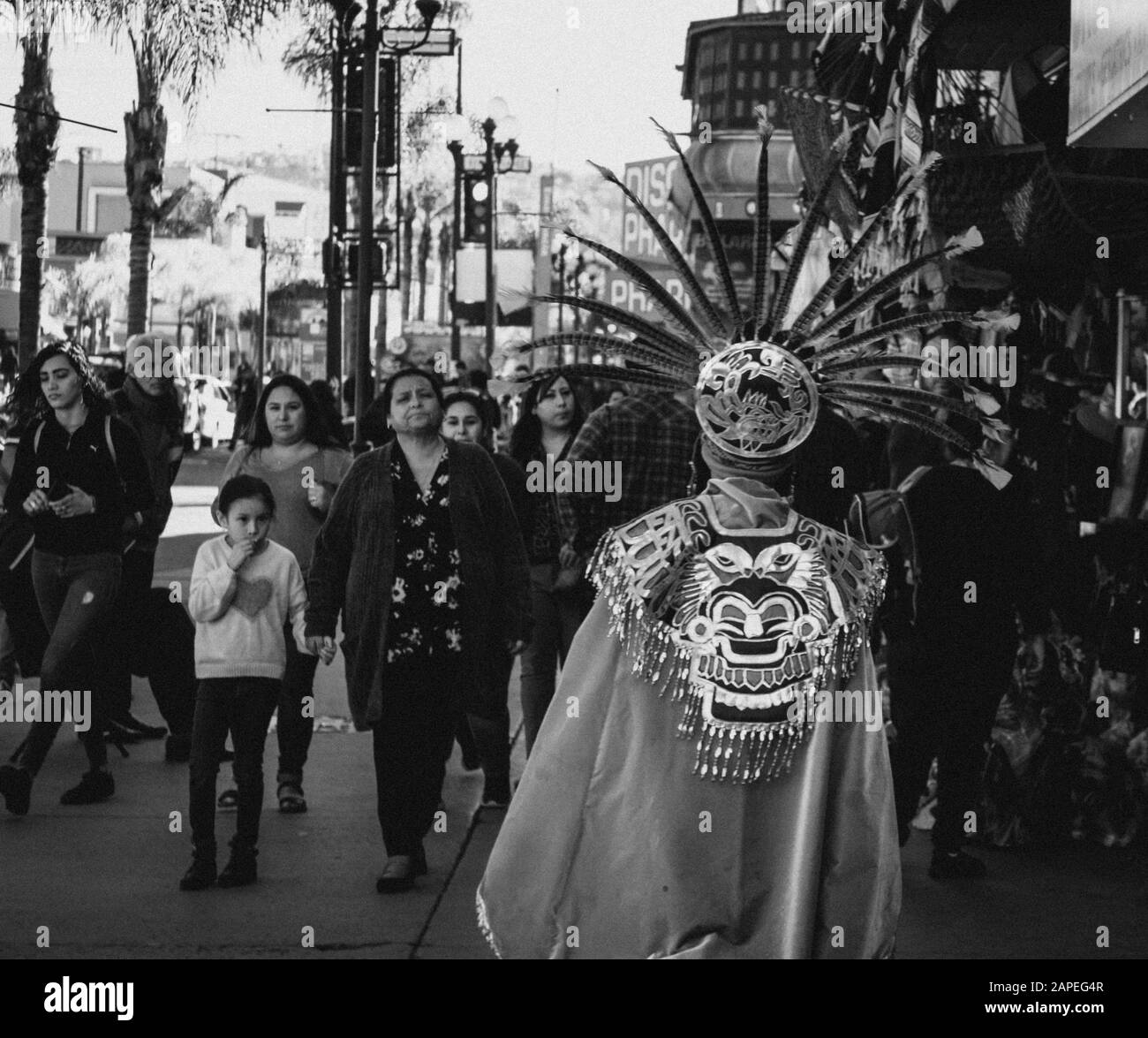 Tijuana Baja California, Mexico - January 18, 2020. Black and white photo of man in Aztec clothing and plume walks among the people of the city. photo Stock Photo