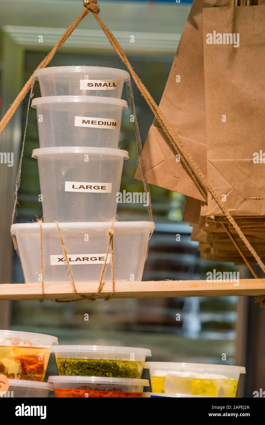 A stack of takeout or take away plastic containers marked with different sizes from small to extra large at a food retailer in the Queen Vic Markets Stock Photo