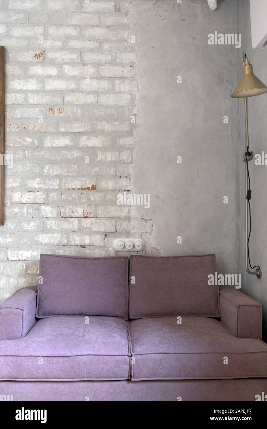Pink sofa against white brick and plastered wall Stock Photo