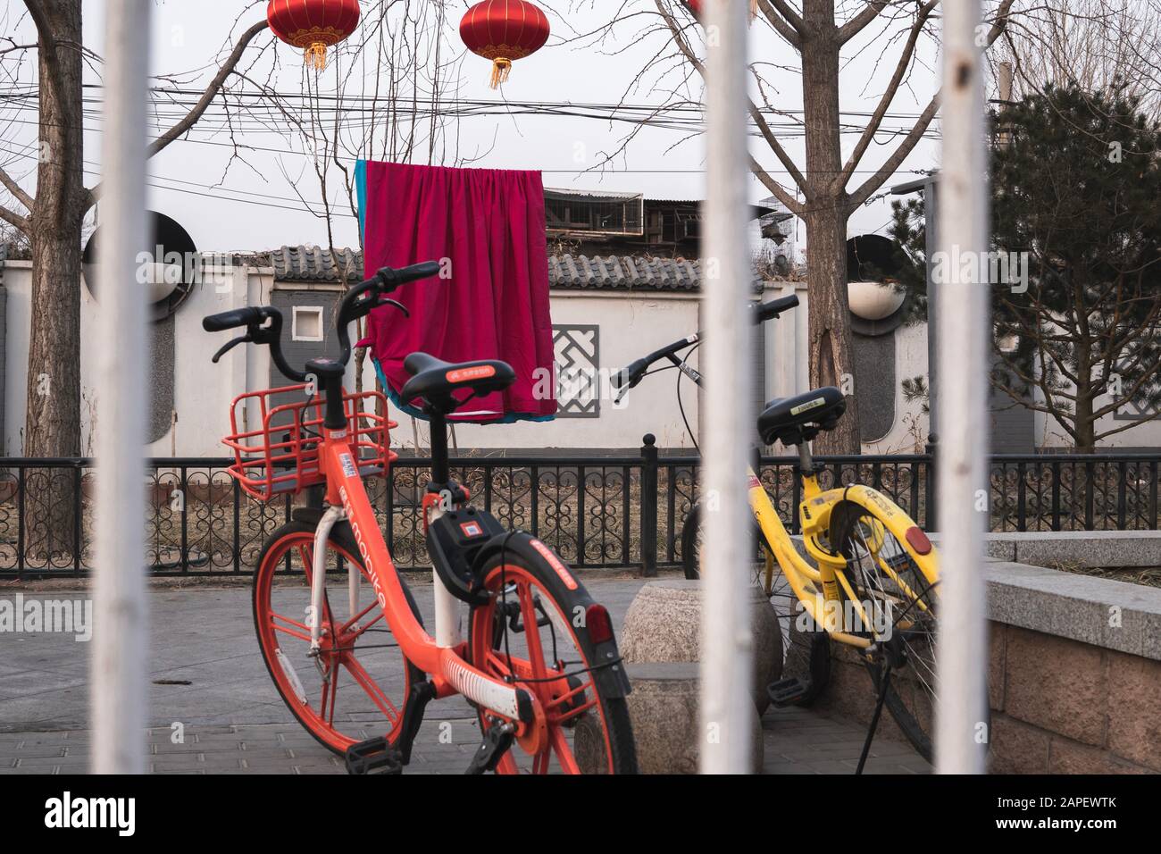 Bicycle sharing in Beijing. Two bicycles on the street in Beijing, China behind a railing. Red lanterns in background, during Chinese New Year. Stock Photo