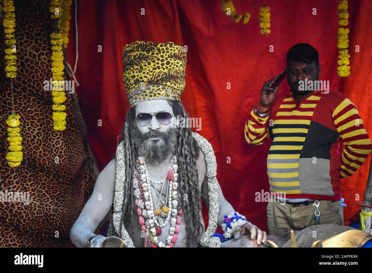 A man is talking to his mobile beside of a Naga Sadhu in a Ganga Sagar Transist Camp at Kolkata, India. Stock Photo