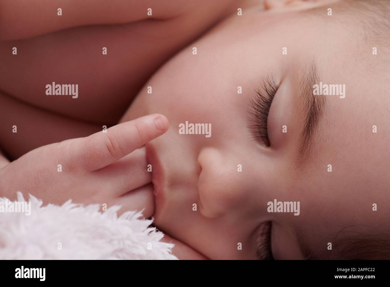 Baby girl sucking finger close up view Stock Photo