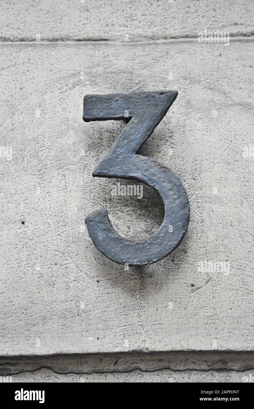 A house number plaque, showing the number three (3) Stock Photo
