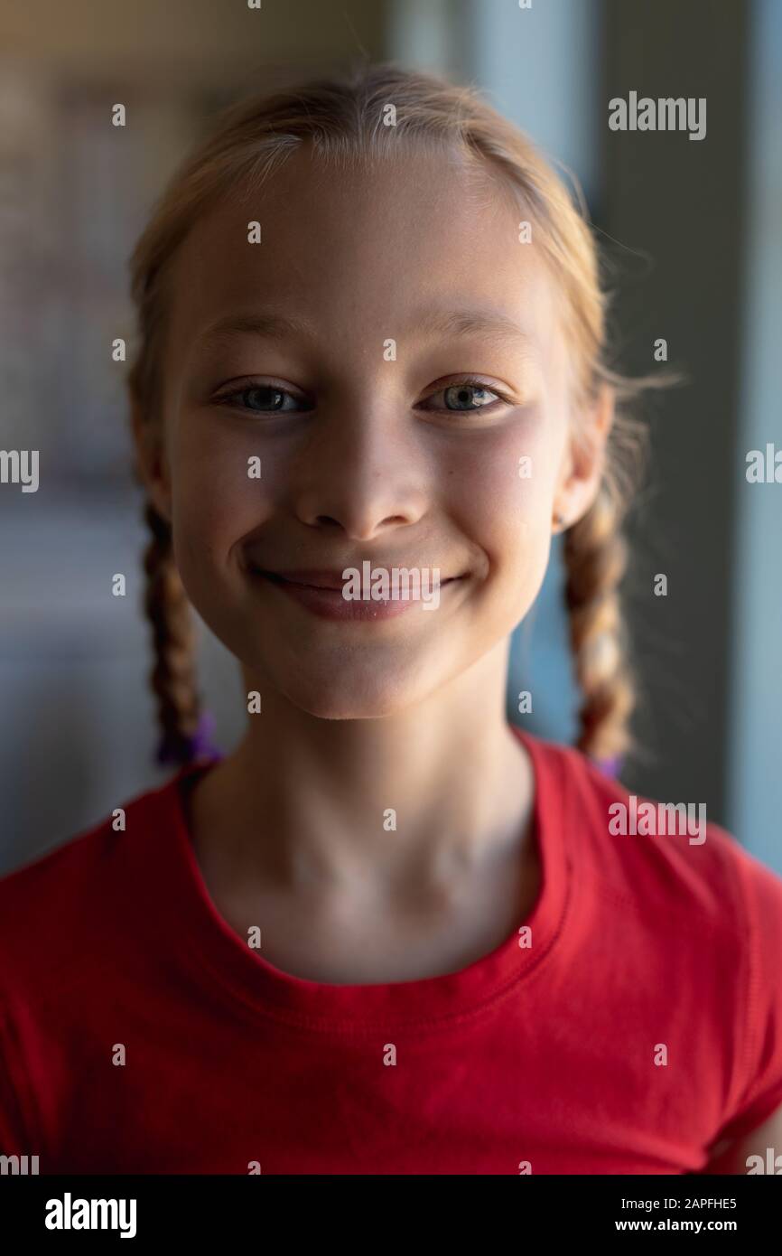 Schoolgirl with blonde hair in plaits looking to camera in an elementary school classroom Stock Photo