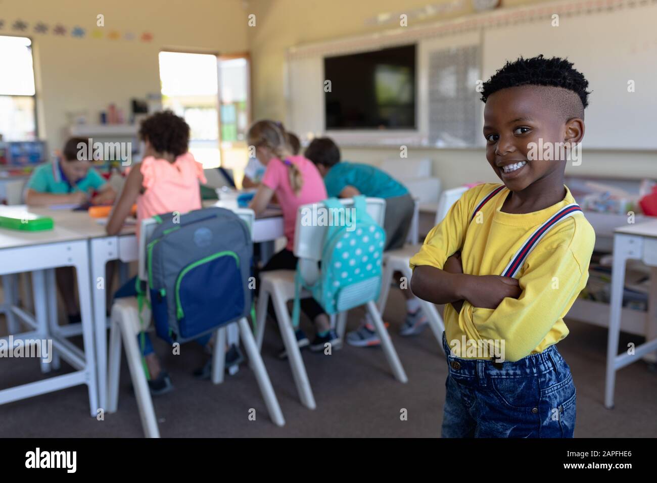 Schoolboy standing with arms crossed in an elementary school classroom